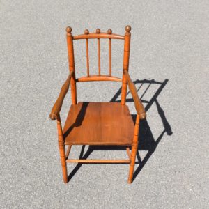 Petite chaise de poupée ou d'enfant en bois. Fabrication du début du XXème siècle. Petit fauteuil avec accoudoirs et pieds en bois tourné. Finition bois naturel teinté.