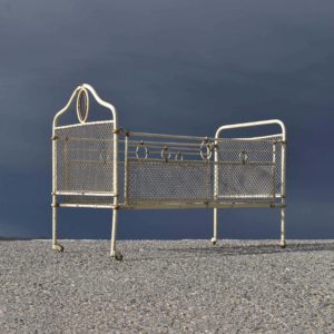 Lit pliable en fer forgé, début du siècle. Petit format: Soit pour un bébé, ou alors grande poupée. Sur roulettes, avec entourage grillagé.