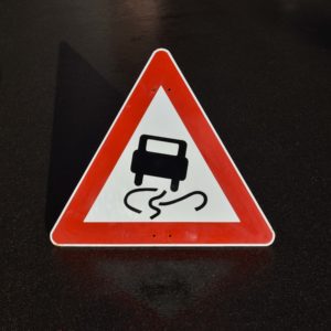 Panneau de signalisation routière Allemand triangulaire : Danger de verglas route glissante. Pictogramme d'une voiture qui glisse.