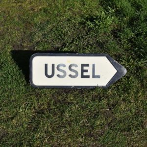 Ussel ville de Corrèze panneau routier vintage flèche de direction. En tôle peinte. Label “Armur” Sureau Nice, des années 1960.