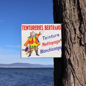 Ancienne plaque émaillée en potence, Teintureries Bertrand Épinal. Avec illustration d'un chat botté. Texte : Teinture, nettoyage, blanchissage.