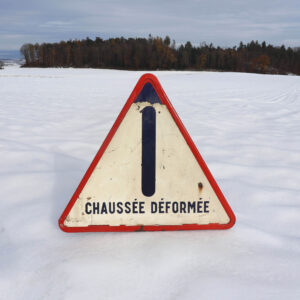 Route déformée ancien panneau de danger en tôle émaillée. Triangulaire, avec revêtement réfléchissant collé, sur fond bleu. Daté de 1965, fabricant signaux Girod Morez.