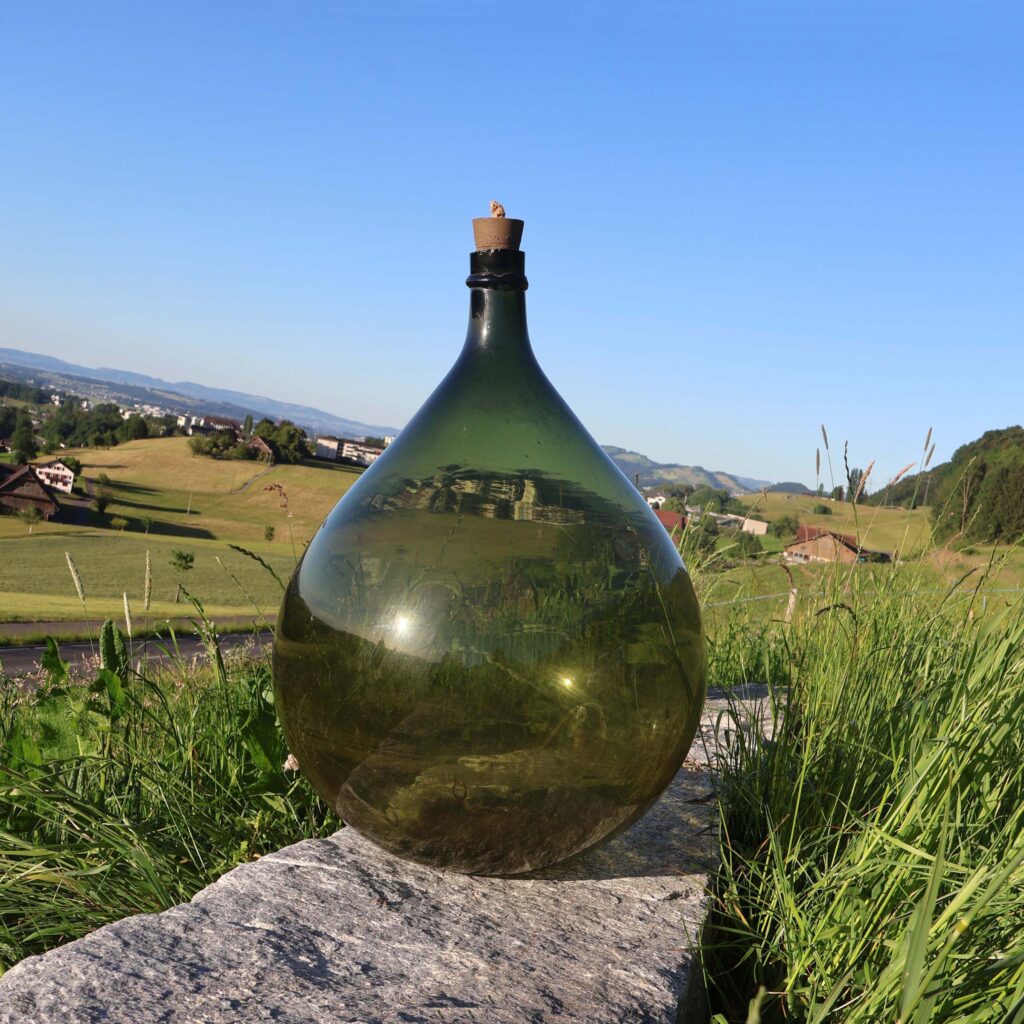 Grande bonbonne dame-jeanne. En verre vert.